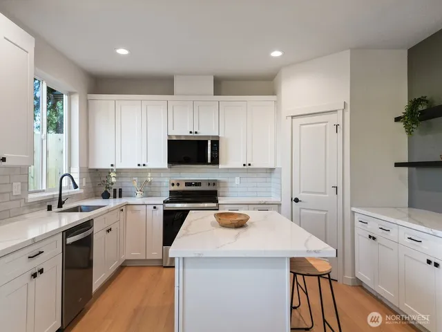 a kitchen with white cabinets sink and stainless steel appliances