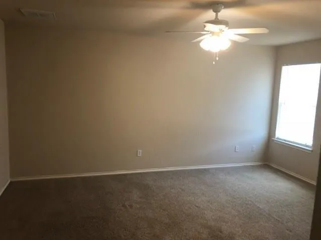an empty room with a window and a fan