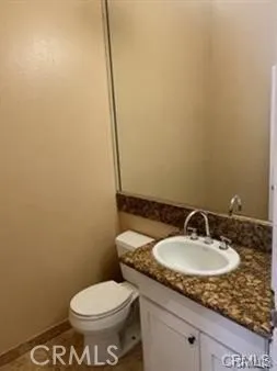 a bathroom with a granite countertop sink and a toilet
