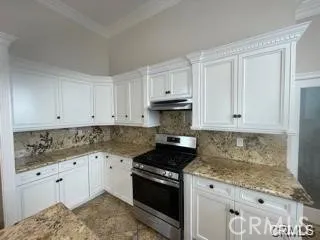 a kitchen with granite countertop white cabinets and stainless steel appliances