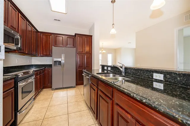 a kitchen with stainless steel appliances granite countertop a refrigerator a stove and a sink with wooden floor