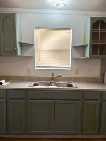 a sink with granite countertop cabinets