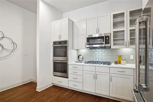 a kitchen with stainless steel appliances white cabinets and a wooden floor