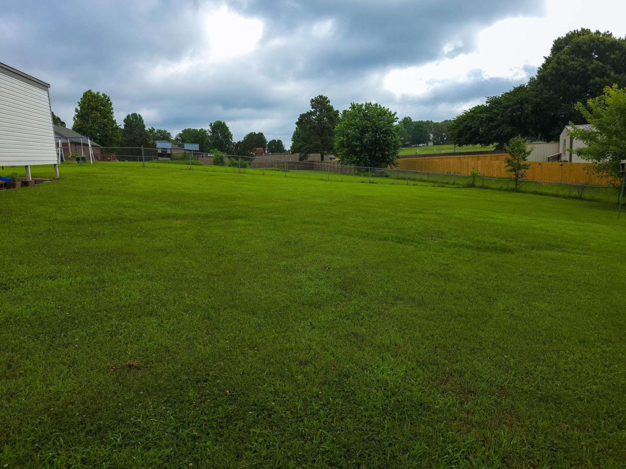 966 Beaver Road Munford, TN 38058 - Photo 8 of 32 Expansive green lawn with a partial white siding structure and a wood privacy fence