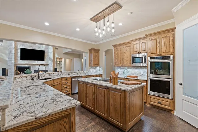 a kitchen with stainless steel appliances granite countertop a stove top oven a sink dishwasher a dining table and chairs with wooden floor