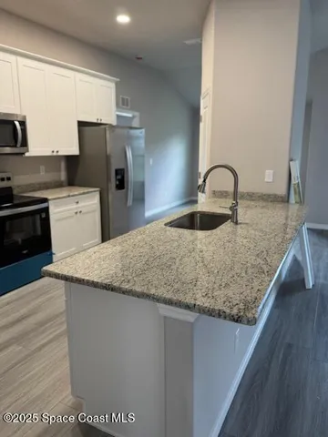 a kitchen with granite countertop a sink a stove and refrigerator