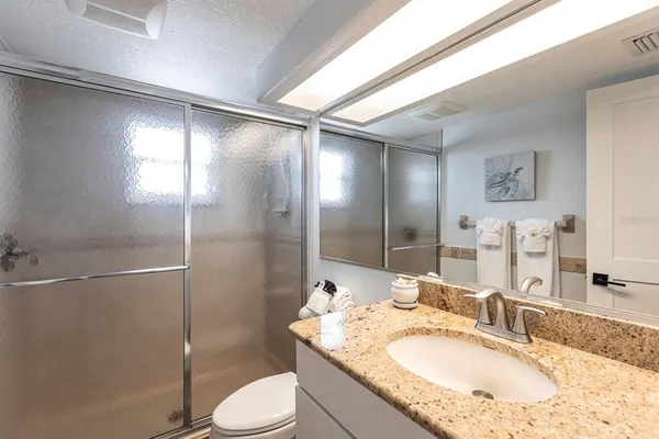 a bathroom with a granite countertop sink toilet and shower