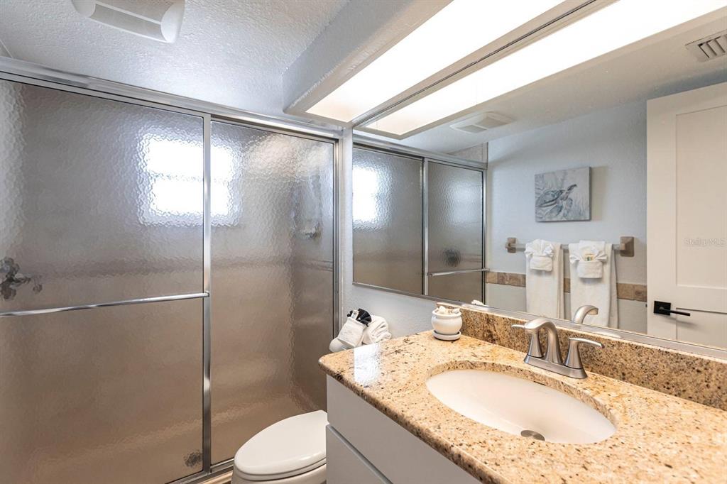 6154 Midnight Pass Road, Unit 202 Sarasota, FL 34242 - Photo 17 of 26 a bathroom with a granite countertop sink toilet and shower