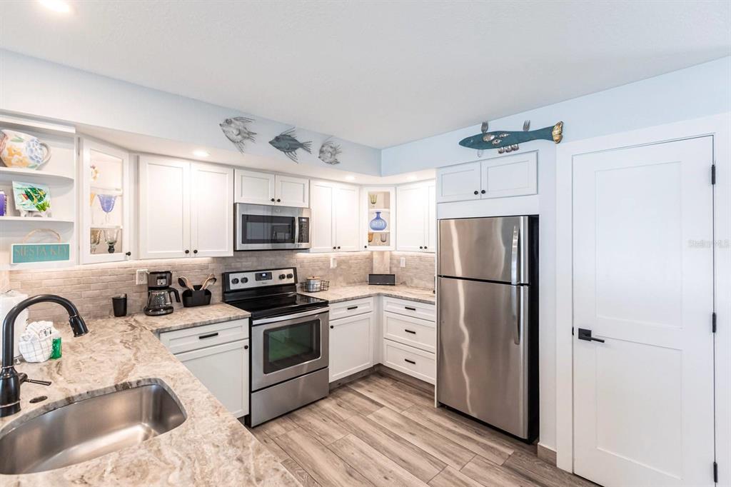 6154 Midnight Pass Road, Unit 202 Sarasota, FL 34242 - Photo 23 of 26 a kitchen with stainless steel appliances a refrigerator sink and microwave