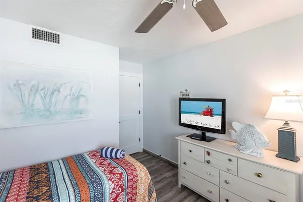 a bedroom with a bed and a flat tv screen on dresser