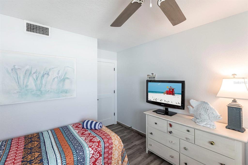 6154 Midnight Pass Road, Unit 202 Sarasota, FL 34242 - Photo 7 of 26 a bedroom with a bed and a flat tv screen on dresser