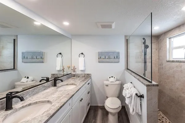 a bathroom with a granite countertop toilet sink and mirror
