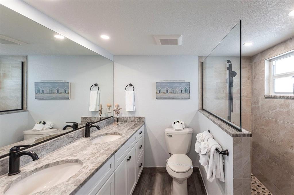 6154 Midnight Pass Road, Unit 202 Sarasota, FL 34242 - Photo 9 of 26 a bathroom with a granite countertop toilet sink and mirror