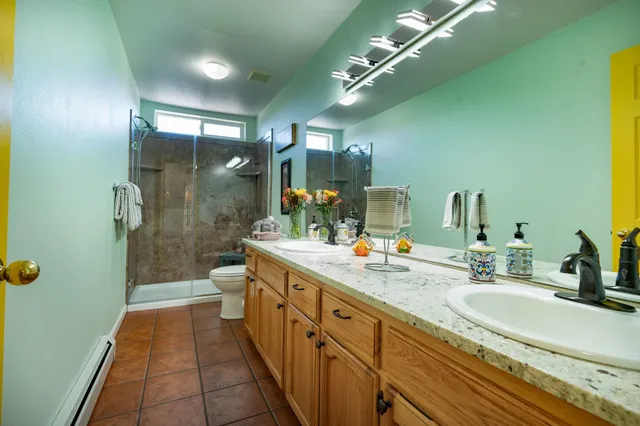 a bathroom with a double vanity sink a toilet a mirror and shower