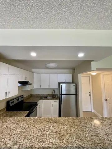 a kitchen with stainless steel appliances granite countertop a refrigerator a sink a stove a microwave and white cabinets