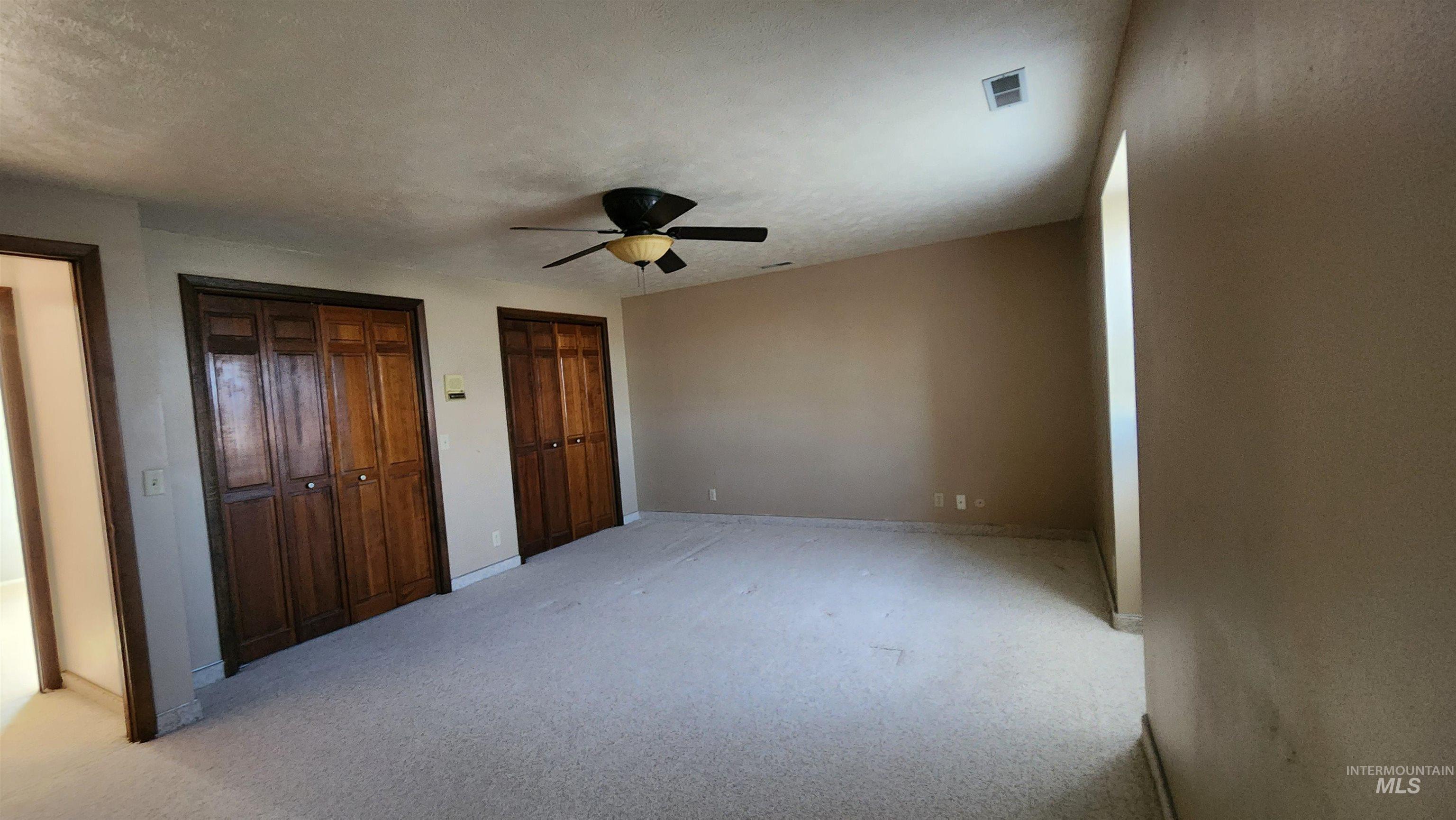 288 South 123 West Burley, ID 83318 - Photo 19 of 36 Unfurnished bedroom with multiple closets, carpet floors, a ceiling fan, and a textured ceiling
