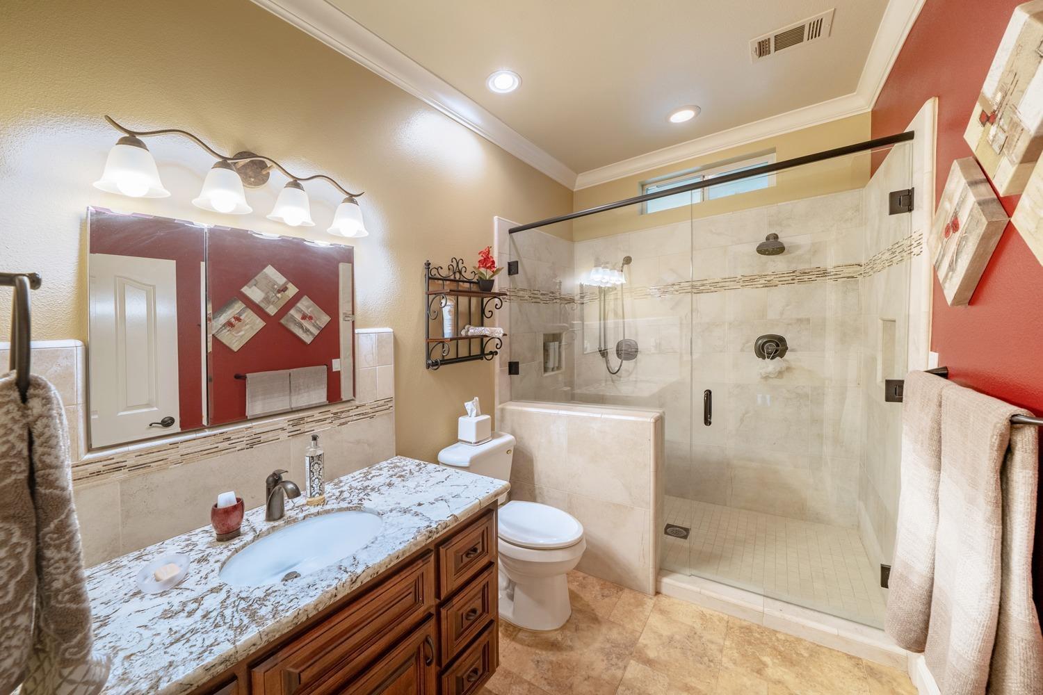 1290 North Applegate Avenue Fresno, CA 93737 - Photo 18 of 65 a bathroom with a granite countertop sink a toilet a mirror a vanity and shower
