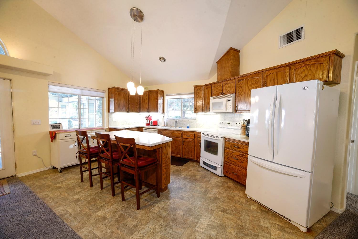 1290 North Applegate Avenue Fresno, CA 93737 - Photo 60 of 65 a kitchen with a refrigerator a dining table and chairs