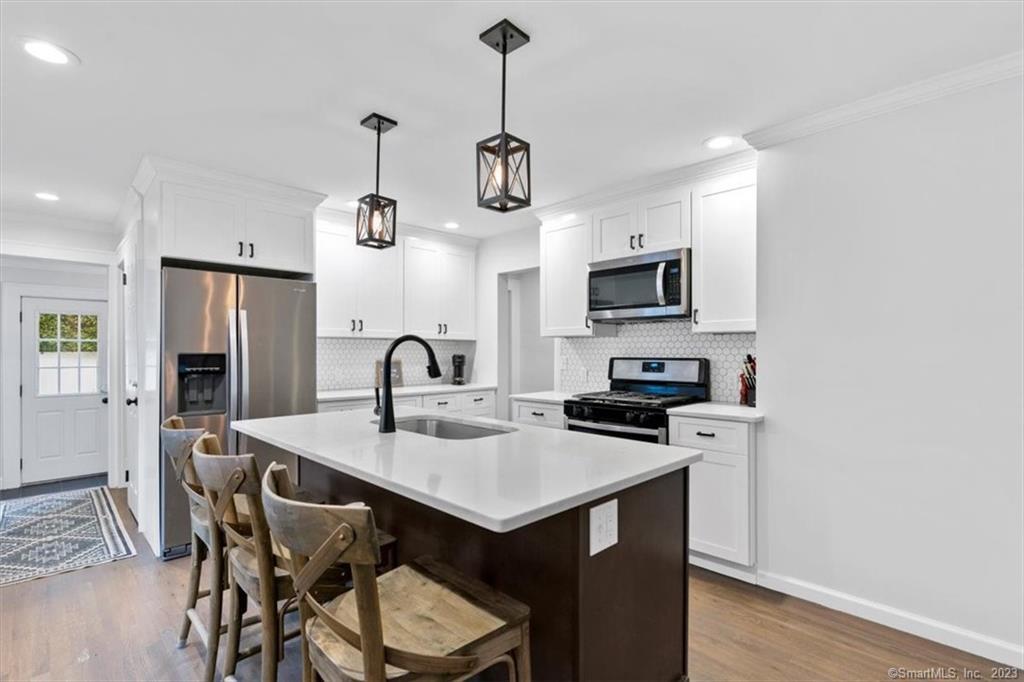 a kitchen with stainless steel appliances granite countertop a sink a stove a refrigerator with a dining table and chairs