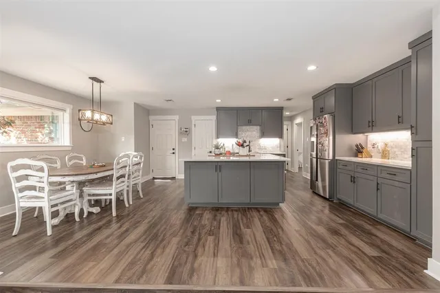 a large kitchen with kitchen island a island in the center and stainless steel appliances