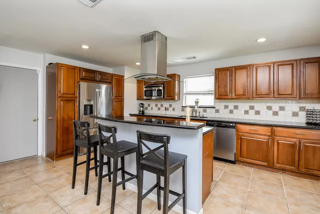 a kitchen with stainless steel appliances granite countertop wooden cabinets a stove a sink and a microwave