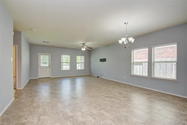 an empty room with chandelier and windows
