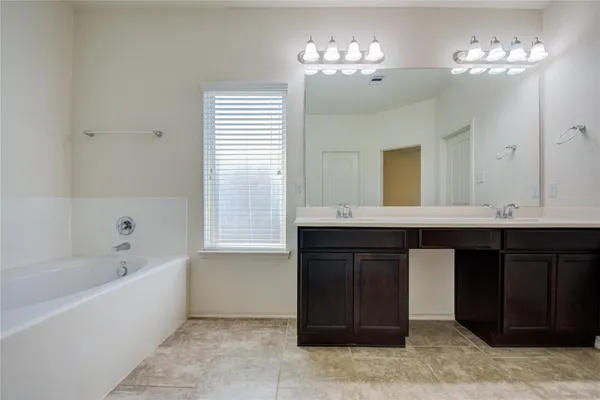 a bathroom with a tub a double vanity sink and a mirror