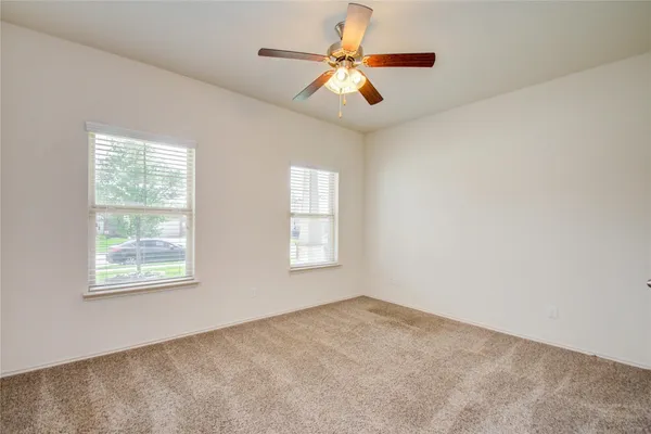 an empty room with windows and fan