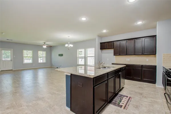 a kitchen with kitchen island granite countertop a stove top oven a sink dishwasher and cabinets with wooden floor