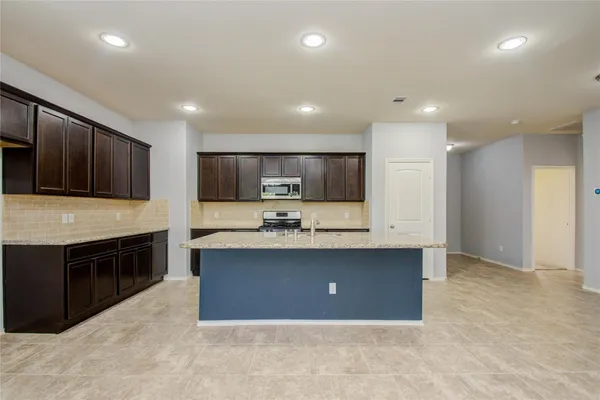 a large kitchen with stainless steel appliances granite countertop a stove refrigerator and a sink