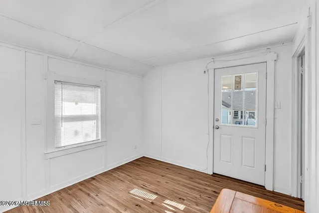 a view of an empty room with window and wooden floor