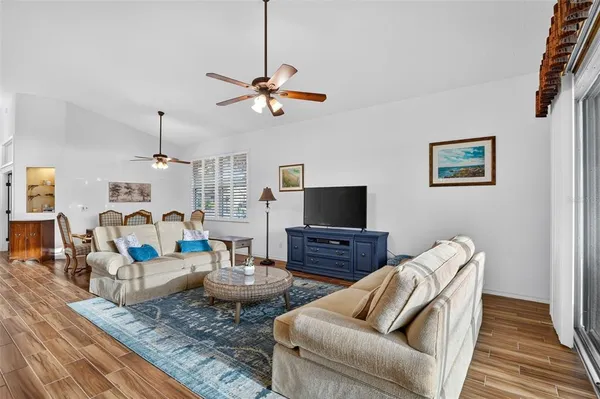 a living room with lots of furniture kitchen view and a chandelier