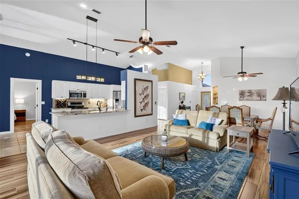a living room with furniture kitchen view and a wooden floor