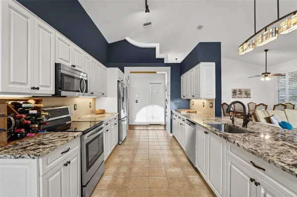 a kitchen with stainless steel appliances granite countertop a sink a stove and a wooden floors