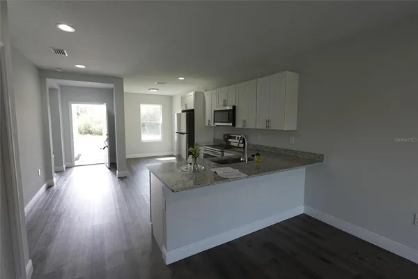 a kitchen with stainless steel appliances granite countertop a sink stove and wooden floor