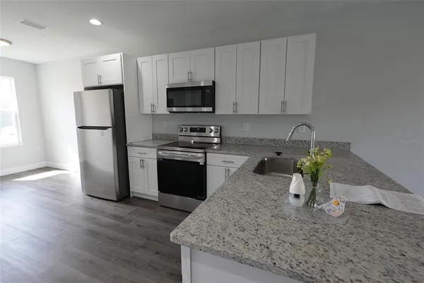 a kitchen with stainless steel appliances granite countertop a refrigerator sink stove microwave and cabinets
