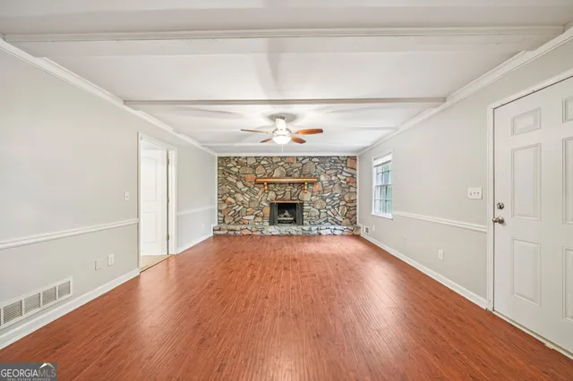 a view of an empty room with wooden floor fireplace and a window
