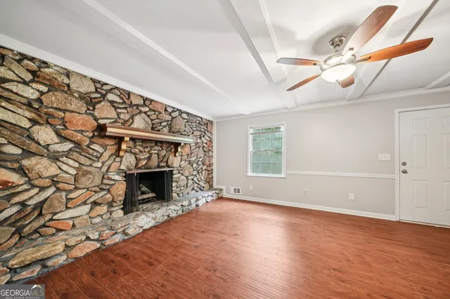 a view of an empty room with wooden floor fireplace and a window