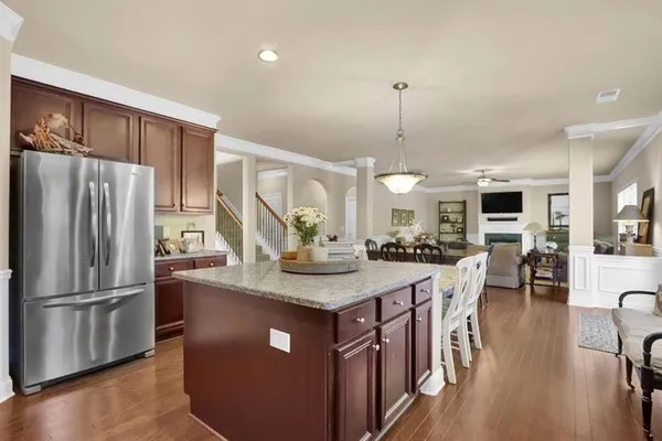 a kitchen with stainless steel appliances granite countertop a refrigerator a stove a sink a dining table and chairs with wooden floor