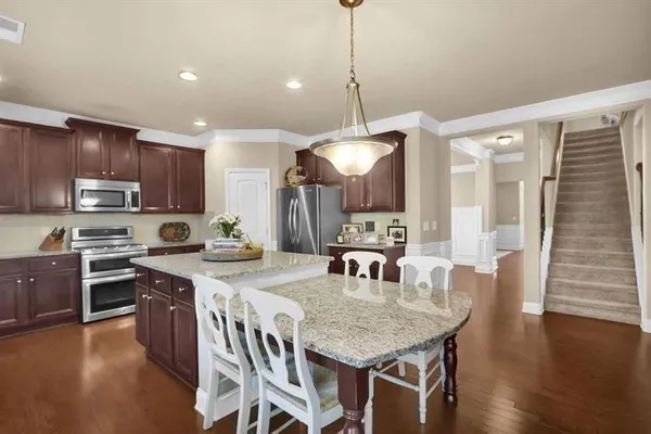 a kitchen with stainless steel appliances granite countertop a kitchen island a stove a table and chairs