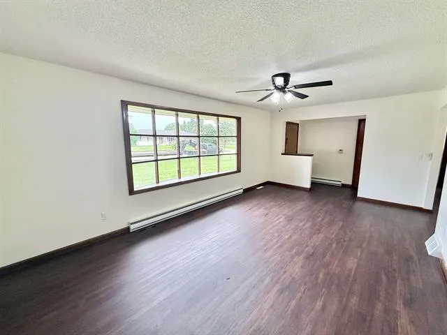 an empty room with wooden floor and ceiling fan