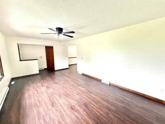 a view of a livingroom with wooden floor and a ceiling fan