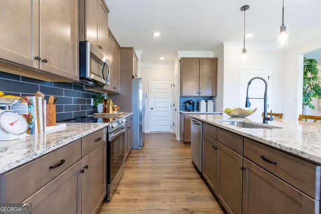 a large kitchen with stainless steel appliances granite countertop a sink a stove and a refrigerator