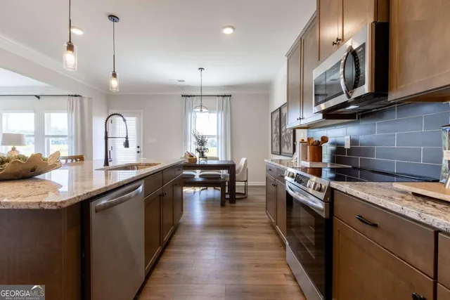 a kitchen with stainless steel appliances granite countertop wooden cabinets a stove a sink and a wooden floors