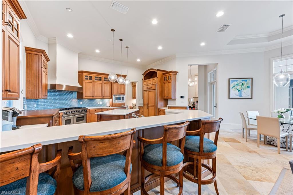 2560 Half Moon Walk Naples, FL 34102 - Photo 5 of 44 Kitchen with wall chimney exhaust hood, pendant lighting, a spacious island, appliances with stainless steel finishes, and ornamental molding