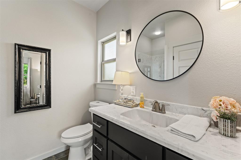 124 Bluffview Circle China Spring, TX 76633 - Photo 22 of 40 Bathroom featuring a dark wood-finish vanity with a white countertop and integrated sink, a large circular mirror with a black frame, and wall-mounted light fixtures