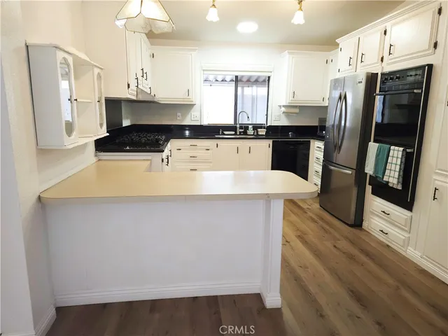 a kitchen with stainless steel appliances a refrigerator a stove a sink and white cabinets