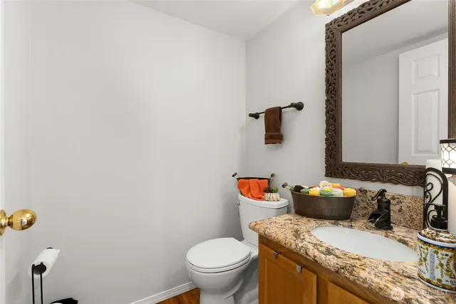 a bathroom with a granite countertop sink and a toilet