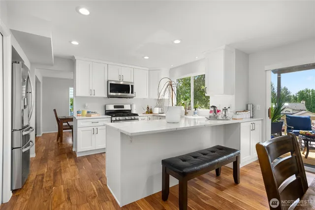 a kitchen with stainless steel appliances a stove top oven a sink dishwasher and a refrigerator with wooden floor