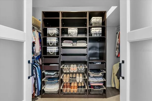 a view of walk in closet with clothes and shoes